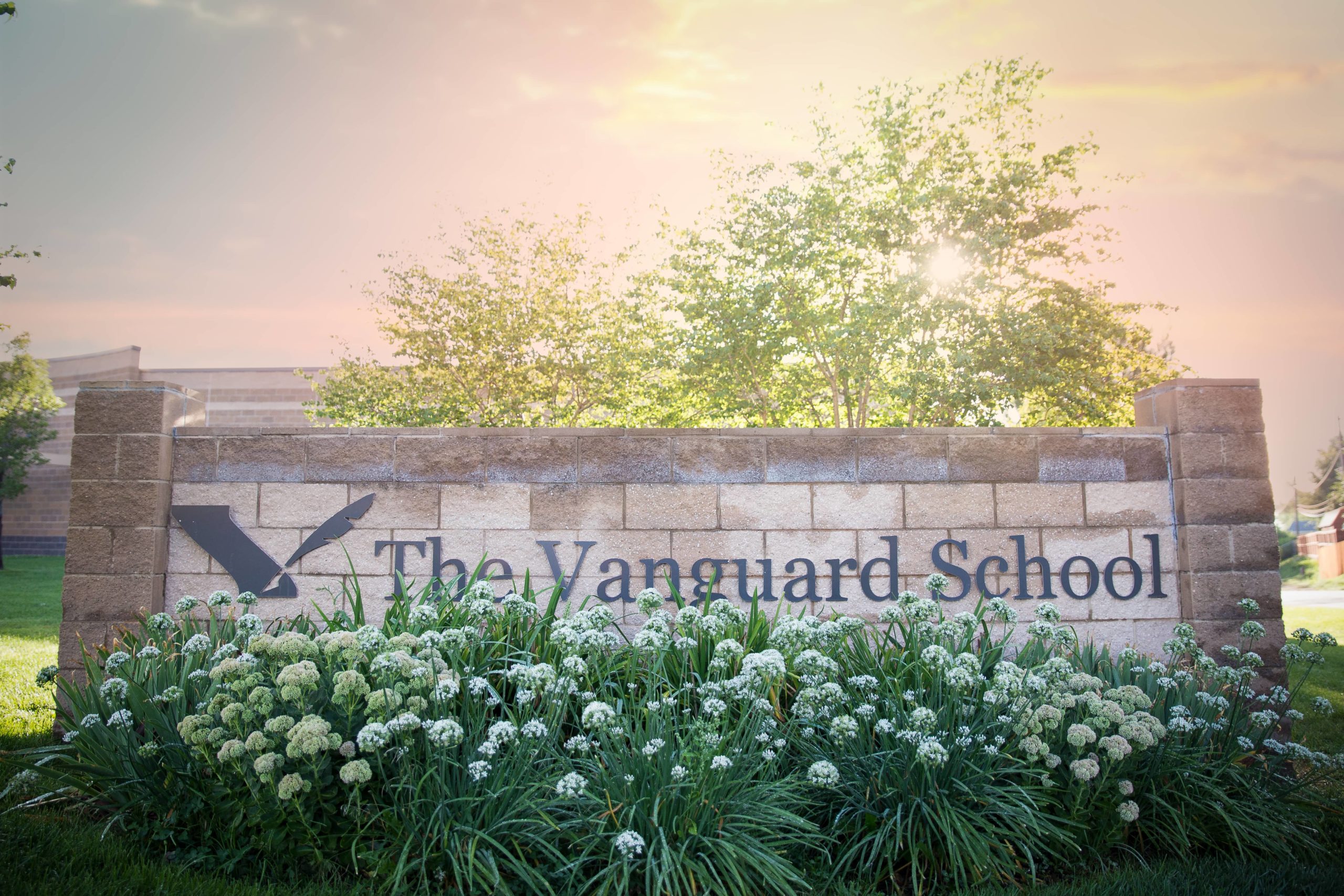 The Vanguard School sign with shrubs and flowers in front